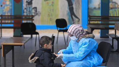 A Palestinian health worker checks the body temperature of a child at a United Nations Relief and Works Agency for Palestinian Refugees (UNRWA) school at Al Shati refugee camp in Gaza City, Palestine on March 18, 2020. AFP