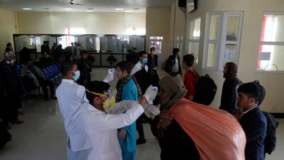 Afghan health workers check the temperatures of Afghan refugees returning at the Islam Qala border crossing with Iran on March 18, 2020. Tens of thousands of Afghan refugees are being expelled from Iran over the past few months. AP Photo